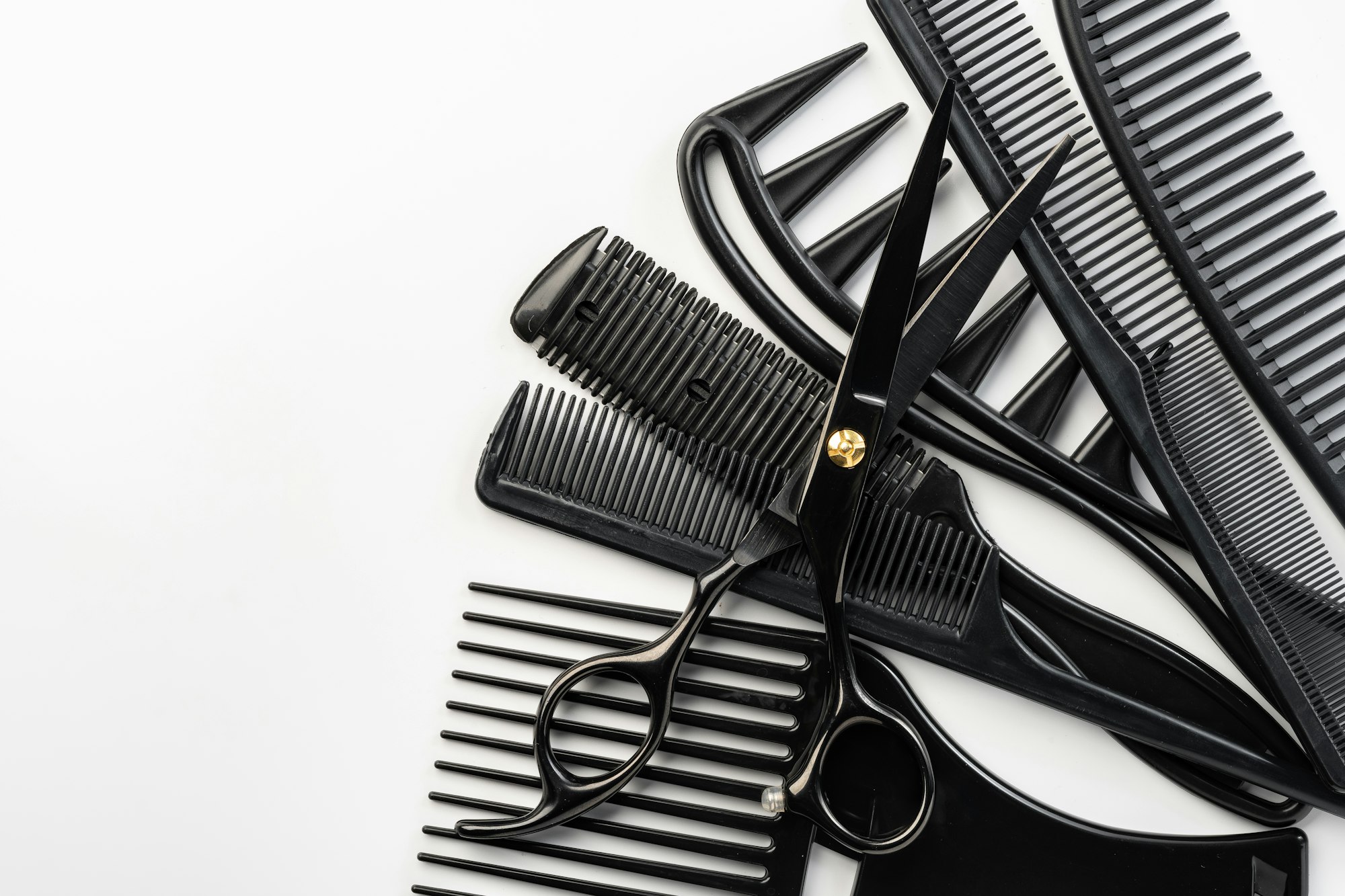 Black hairdressing tools and various hairbrushes on white background