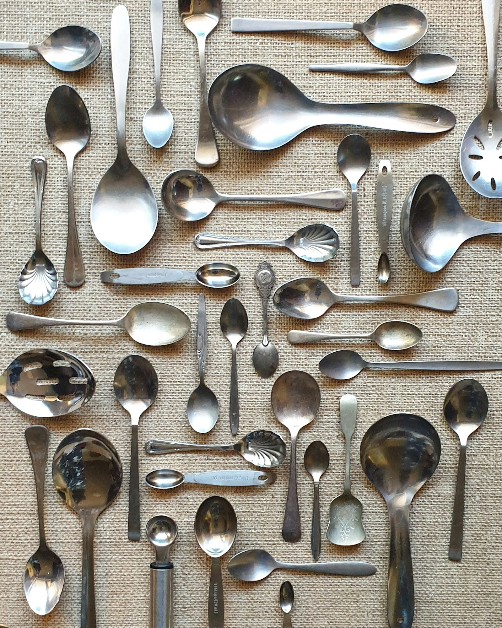 kitchen cutlery silverware spoon collection arranged neatly on table cloth full frame