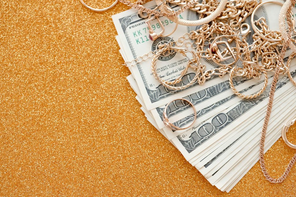 Many expensive golden jewerly rings, earrings and necklaces with big amount of US dollar bills