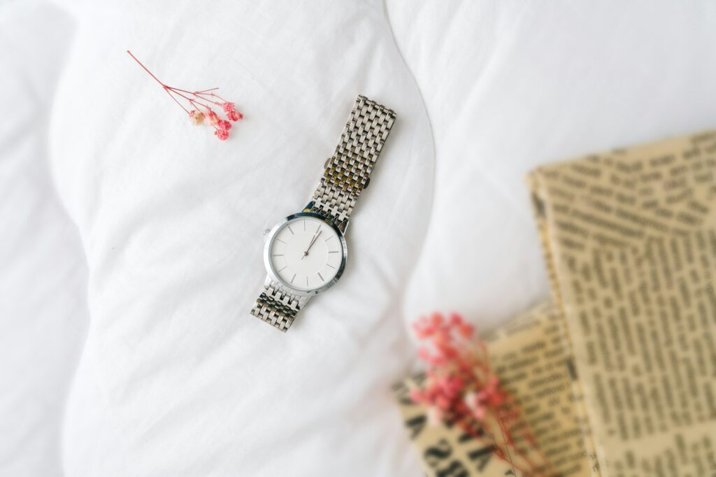Silver watch on white textile top view.